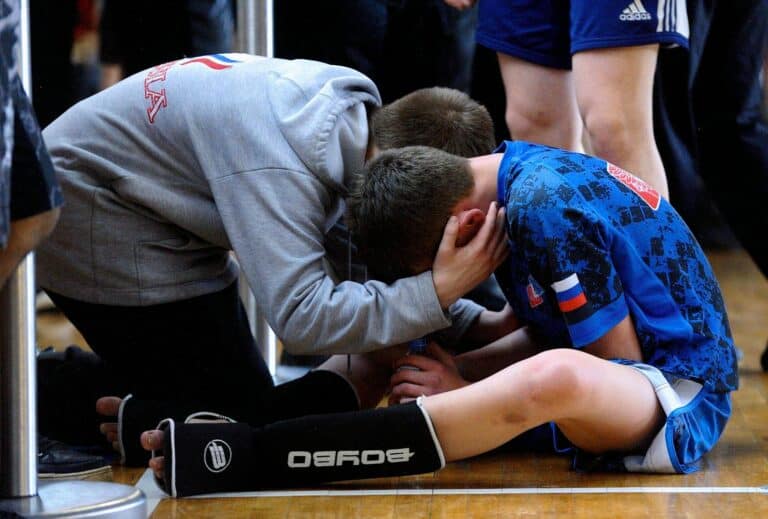 A coach consoles a young athlete after a sports match, highlighting teamwork and motivation.