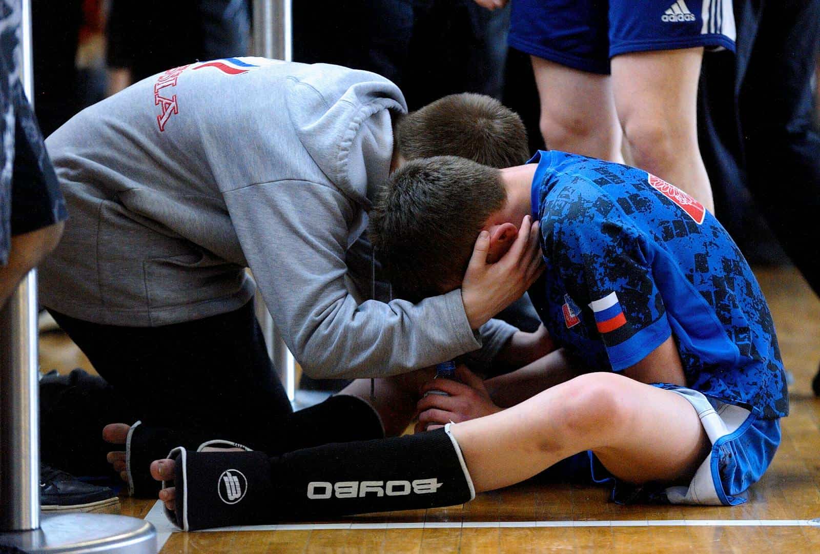 A coach consoles a young athlete after a sports match, highlighting teamwork and motivation.